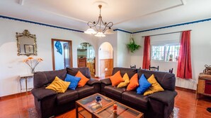 A living room with two sofas, a glass coffee table, and a chandelier.