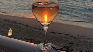 Una copa de vino en un balcón con vista a la puesta de sol sobre el mar.