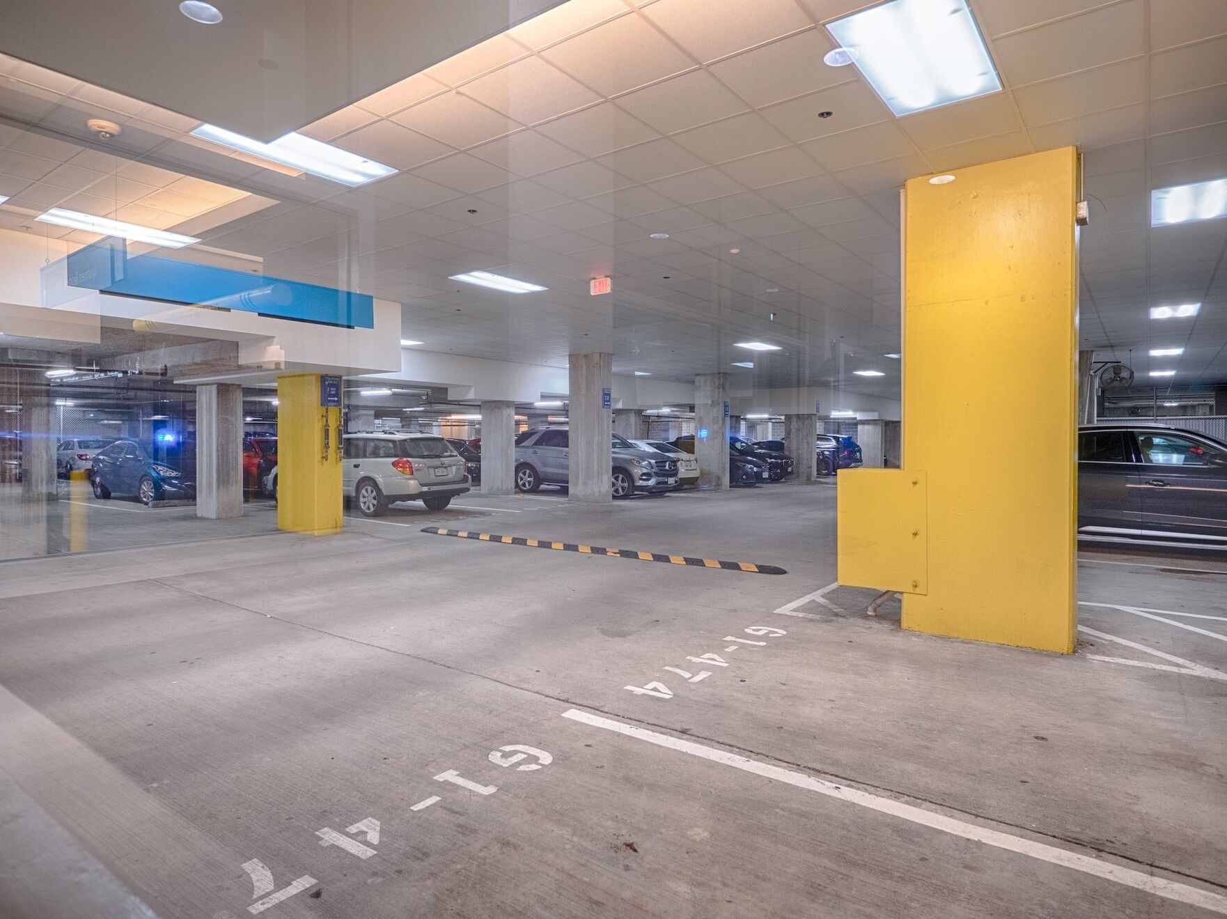 Un parking à plusieurs niveaux, doté de piliers en béton et de places de stationnement délimitées.