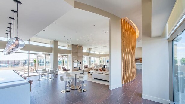 Een ruime woonruimte met een modern design, met een grote zithoek, een keuken en uitzicht op de stad.