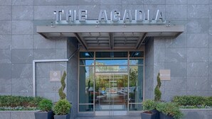 De ingang van The Acadia, met een modern ontwerp, met een glazen gevel en een bord boven de deur.