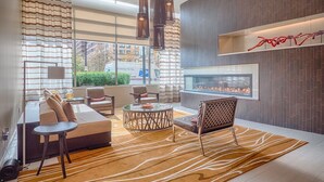 Eine moderne Hotelhalle mit einer Couch, Sesseln, einem Couchtisch und einem Kamin.