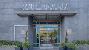 Der Eingang von The Acadia mit modernem Design, gekennzeichnet durch eine Glasfassade und einem Schild über der Tür.