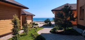 Un bâtiment en bois avec une allée pavée qui mène à un point de vue sur la mer.