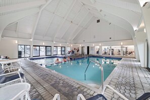 An indoor swimming pool with clear glass walls, a tiled floor, and a high arched ceiling. - Summer House 504B by Liquid Life (Orange Beach)