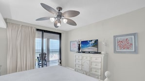 Ein Schlafzimmer mit einem großen Bett, einem Deckenventilator, einer Kommode und einem Fernseher.
