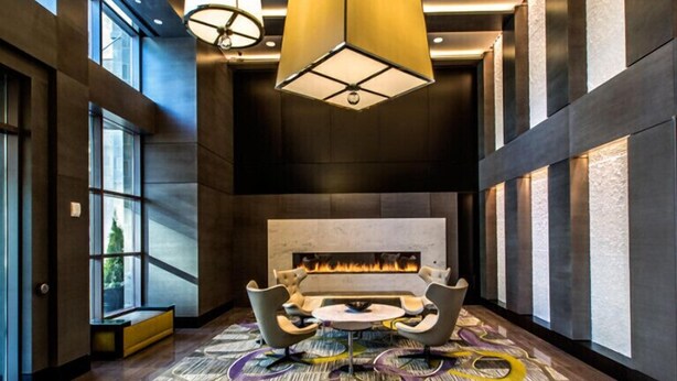 A modern lounge area with a fireplace, comfortable seating, and large windows. - National at Reston Town Center (Reston)