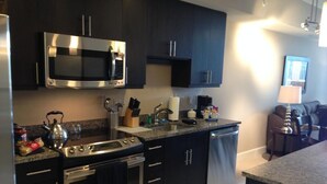 A modern kitchen with dark cabinetry, stainless steel appliances, and a granite countertop. - National at Reston Town Center (Reston)