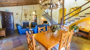 A rustic interior with a wooden dining table, blue leather sofas, a fireplace, and a staircase. - Finca Almencino Cómpeta by Ruralidays (Málaga)