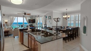 Una cocina espaciosa con una isla grande, un comedor con candelabro y vistas al océano.