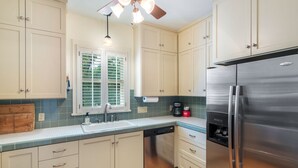A kitchen with light-colored cabinets, a stainless steel refrigerator, a dishwasher, and a window with blinds. - Hyde Park Historic District - Close To Everything Austin Has To Offer! (Austin)