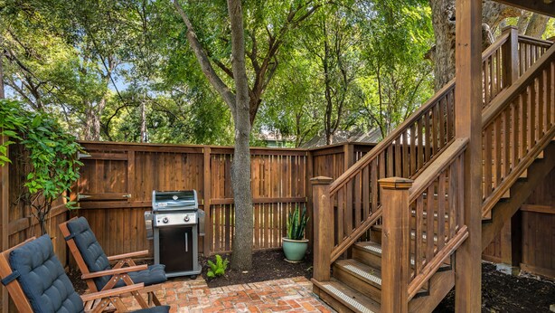 A backyard with a wooden deck, a grill, and two folding chairs. - Hyde Park Historic District - Close To Everything Austin Has To Offer! (Austin)