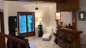 A living room with a sofa, a white armchair, a small table with chairs, a bookshelf, a lamp, and a mirror. - The caminada, house in the heart of the Pyrenees Ariégeoises (Fougax-et-Barrineuf)