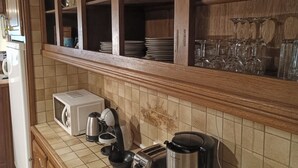 A kitchen with wooden cabinets, a microwave, a toaster, a coffee maker, and a tiled backsplash. - The caminada, house in the heart of the Pyrenees Ariégeoises (Fougax-et-Barrineuf)