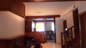A wooden interior with a dining area, a staircase, and a view into another room. - The caminada, house in the heart of the Pyrenees Ariégeoises (Fougax-et-Barrineuf)