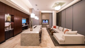 A modern living room with a large sofa, a coffee table, and a TV mounted on the wall. - National Tysons Corner (McLean)