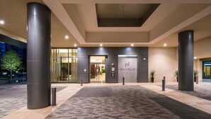 A modern hotel entrance with a glass facade, a brick wall, and a name sign. - National Tysons Corner (McLean)