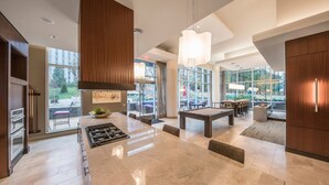 A modern kitchen with a central island, a dining area with a pool table, and large windows offering views of the outdoors. - National Tysons Corner (McLean)