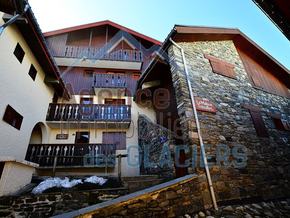 A multi-story building with balconies, stone walls, and a sign reading "La Maison Tresalet."