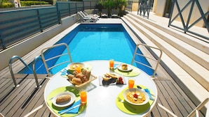 A poolside dining table with breakfast items and a view of the pool. - Villa w/ BBQ & pool near the Strip, Albufeira (Albufeira)