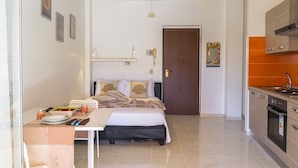 A compact hotel room with a bed, bedside table, and a small kitchenette. - Soleil Suite in Giardini Naxos (Giardini Naxos)