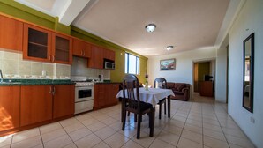 A spacious kitchen with wooden cabinets, a dining table, and chairs. - Hotel de Santa Maria (Santa Cruz del Quiché)