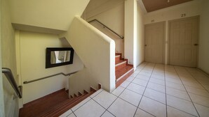 A staircase with handrails, a mirror, and a tiled floor leading to a door marked with the number 23. - Hotel de Santa Maria (Santa Cruz del Quiché)