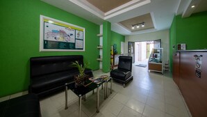 A reception area with green walls, black leather seating, a reception desk, and a map on the wall. - Hotel de Santa Maria (Santa Cruz del Quiché)