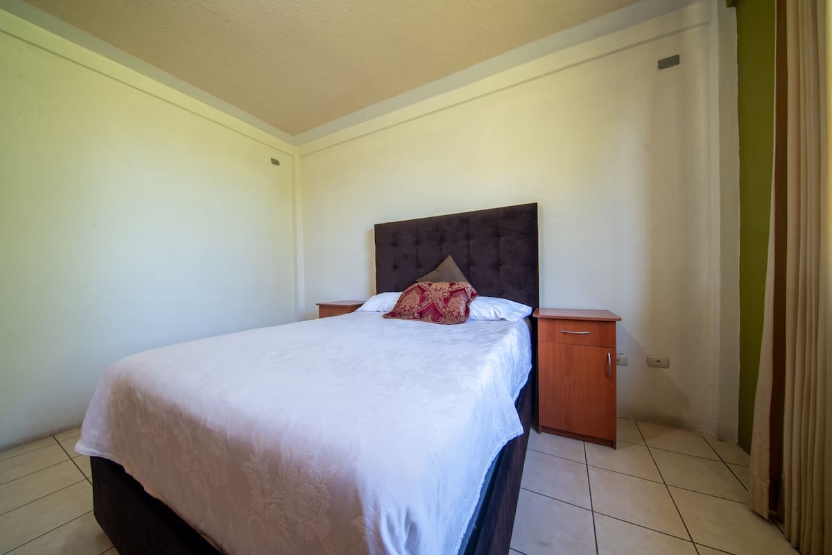 Un dormitorio con una cama, una mesita de noche y un aparador de madera.