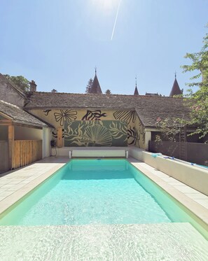 Relax by the serene pool surrounded by a beautifully tiled deck and a vibrant mural.