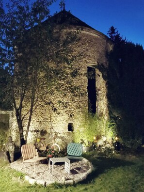 Relax in a serene garden setting surrounded by lush greenery and a historic stone building with a charming circular tower.