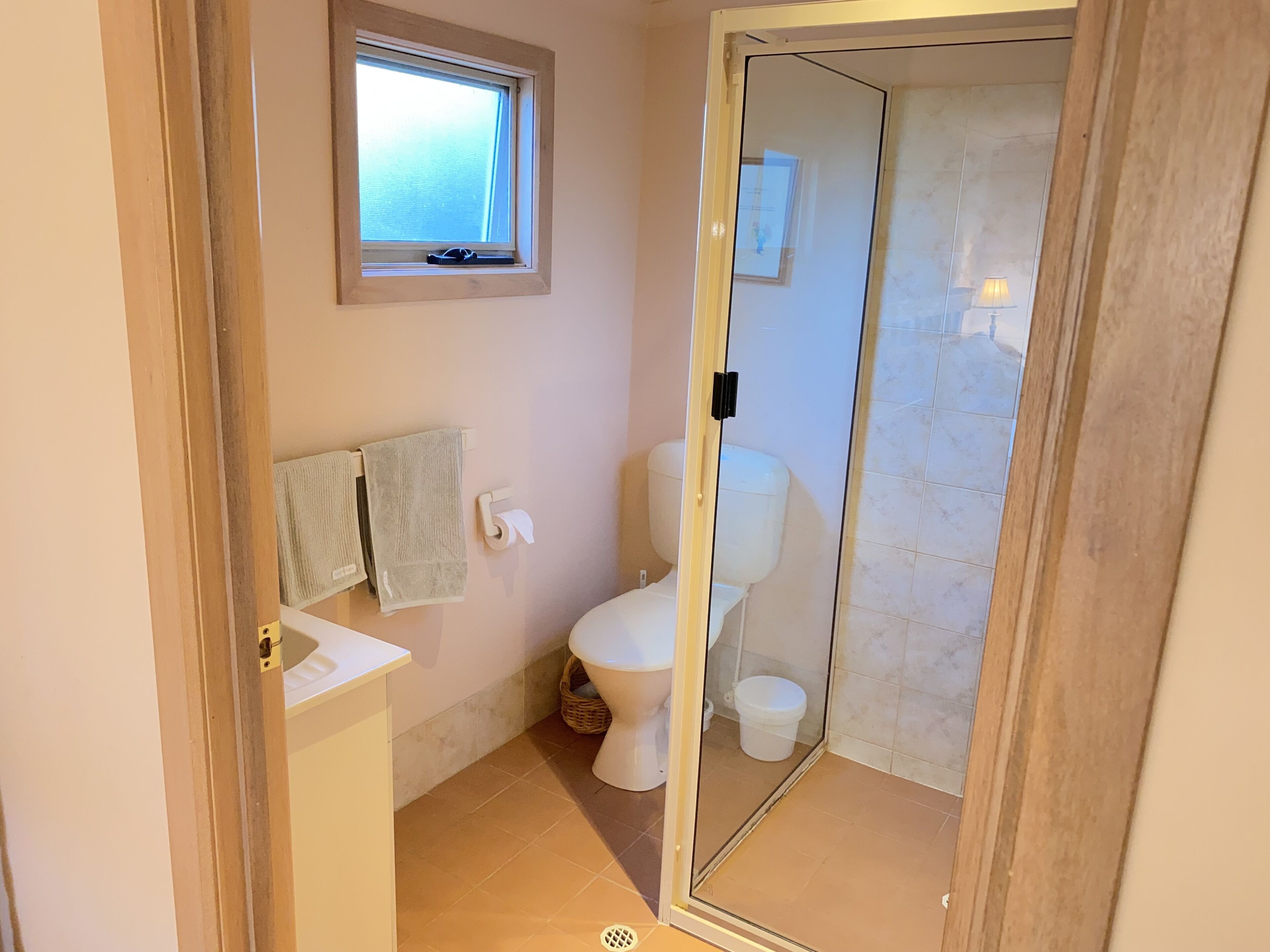 Un baño con inodoro, lavamanos, ventana y zona de ducha.