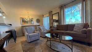 Ein Wohnzimmer mit einer Couch, Sesseln, einem Couchtisch und einem Essbereich mit Tisch und Stühlen.