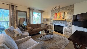 Ein Wohnzimmer mit Kamin, einer Couch, einem Couchtisch und einem Fernseher.
