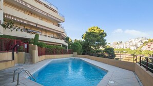 A rectangular swimming pool with a metal ladder on one side, surrounded by a tiled deck. - Appartement Lanterne – Welkeys (Nice)
