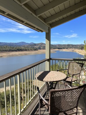 A covered outdoor area with a table and chairs, overlooking a lake and mountains.