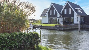 A modern house with a dock, surrounded by water and greenery.