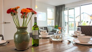A dining table set with a vase of flowers, a bottle of wine, and glasses.