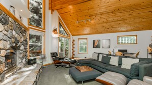 A modern living room with a stone fireplace, a large sectional sofa, and a wooden ceiling. - Star Pine_Luxury w/Game Room, Pool Table & HOA Amenities (Hot Tub/Sauna/Gym) (Truckee)