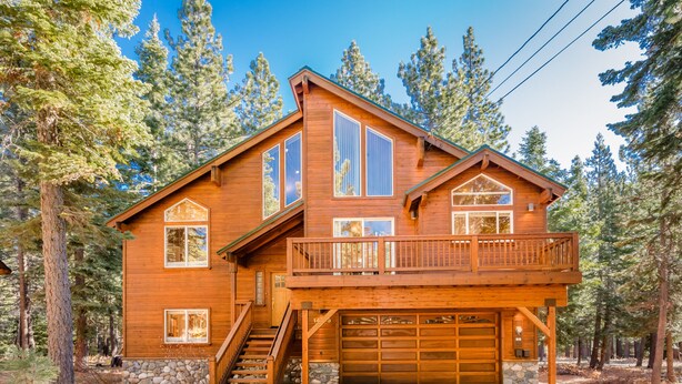 A two-story wooden cabin with a balcony, a garage, and a stone foundation. - Star Pine_Luxury w/Game Room, Pool Table & HOA Amenities (Hot Tub/Sauna/Gym) (Truckee)