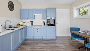A modern kitchen with blue cabinets, a white countertop, and a built-in oven. - Rafters -  a lodge that sleeps 2 guests  in 1 bedroom (Georgeham)