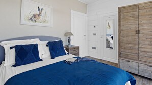 A bedroom with a bed, a nightstand, a lamp, a wardrobe, and a painting on the wall. - Rafters -  a lodge that sleeps 2 guests  in 1 bedroom (Georgeham)