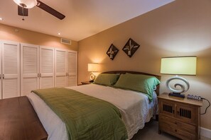 Ein Schlafzimmer mit Bett, Nachttischen, einer Lampe und einem Deckenventilator.