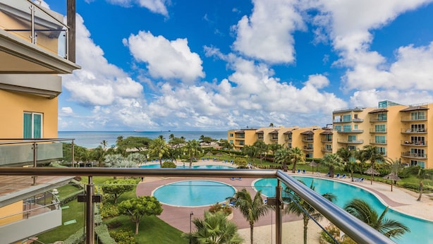 Een resort met meerdere zwembaden, weelderige begroeiing en uitzicht op de oceaan.