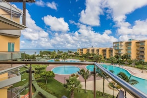 Ein Resort mit mehreren Schwimmbecken, üppiger Vegetation und Blick aufs Meer.