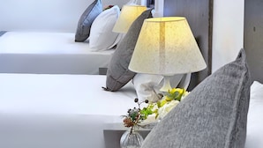 Une chambre d’hôtel moderne avec un lit bien fait, une table de chevet avec une lampe et un vase rempli de fleurs.