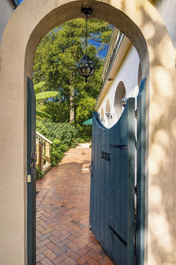 An arched entrance to a property with a blue gate marked '335' and a hanging lantern.