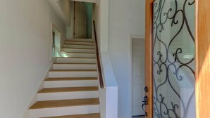 A staircase with wooden steps leading to a door with a decorative glass panel. - Serene Cottage with Lush Landscaped Grounds (Charleston)