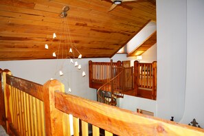 Stunning interior with a high ceiling and staircase leading to an upper level, featuring a window and elegant hanging light fixtures.
