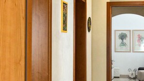 A hallway with wooden doors, a tiled floor, and framed artwork on the walls.